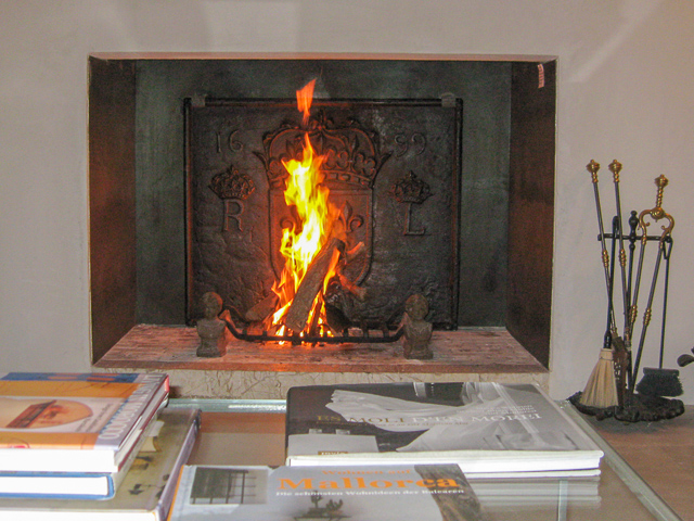 Une cheminée espagnole moderne avec une plaque de cheminée française du 17ème siècle et des chenets du 19ème siècle